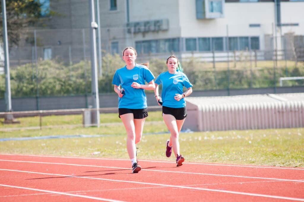 Two girls race around a running track