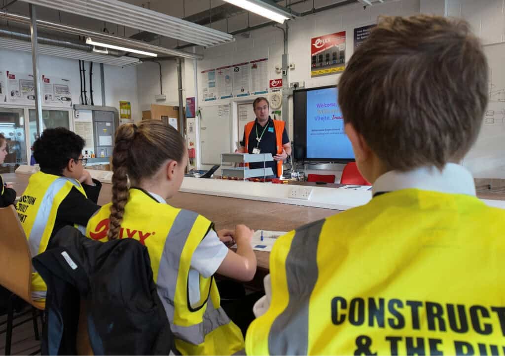 Schoolchildren learn construction at a City College workshop - a male teacher stands in front of the class
