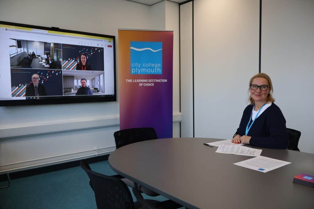 City College Plymouth CEO Jackie Grubb sits at a desk with members of West College Scotland on a screen behind her.